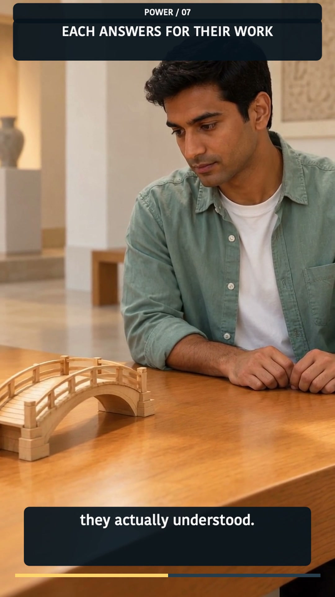 A full portrait frame from the published English story: a team member reflects over a wooden bridge model, with the caption ‘Each answers for their work.’